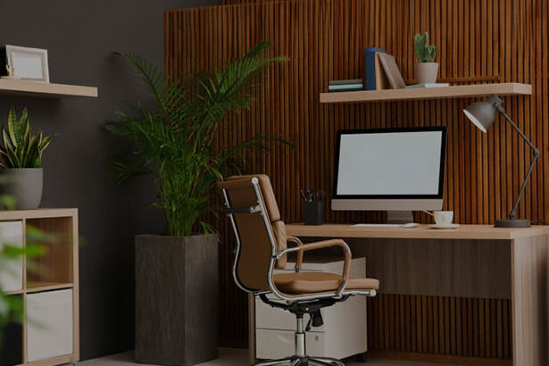 Ένα γραφείο με υπολογιστή, πληκτρολόγιο, και διάφορα γραφικά είδη σε έναν σύγχρονο χώρο γραφείου με διάφορα έπιπλα και φυτά.